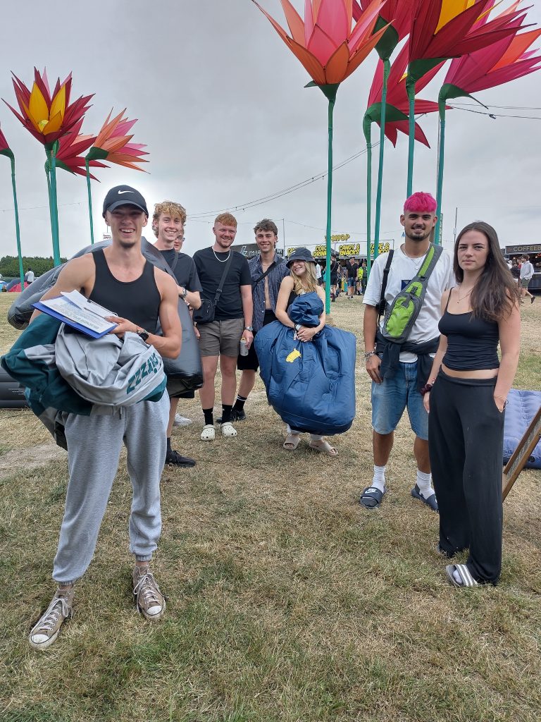 Queue of young people holding deflated air beds at a festival