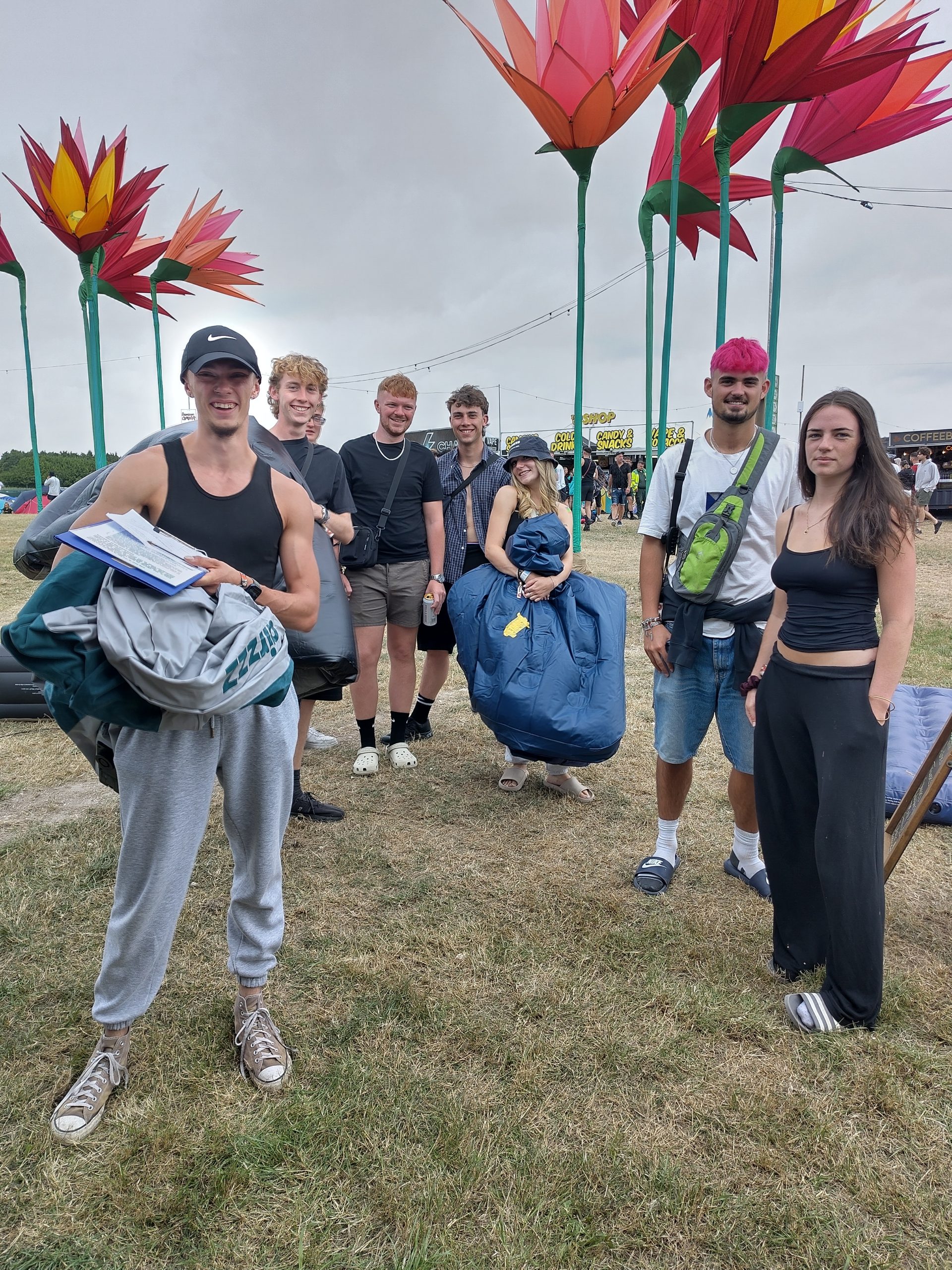 Queue of young people holding deflated air beds at a festival